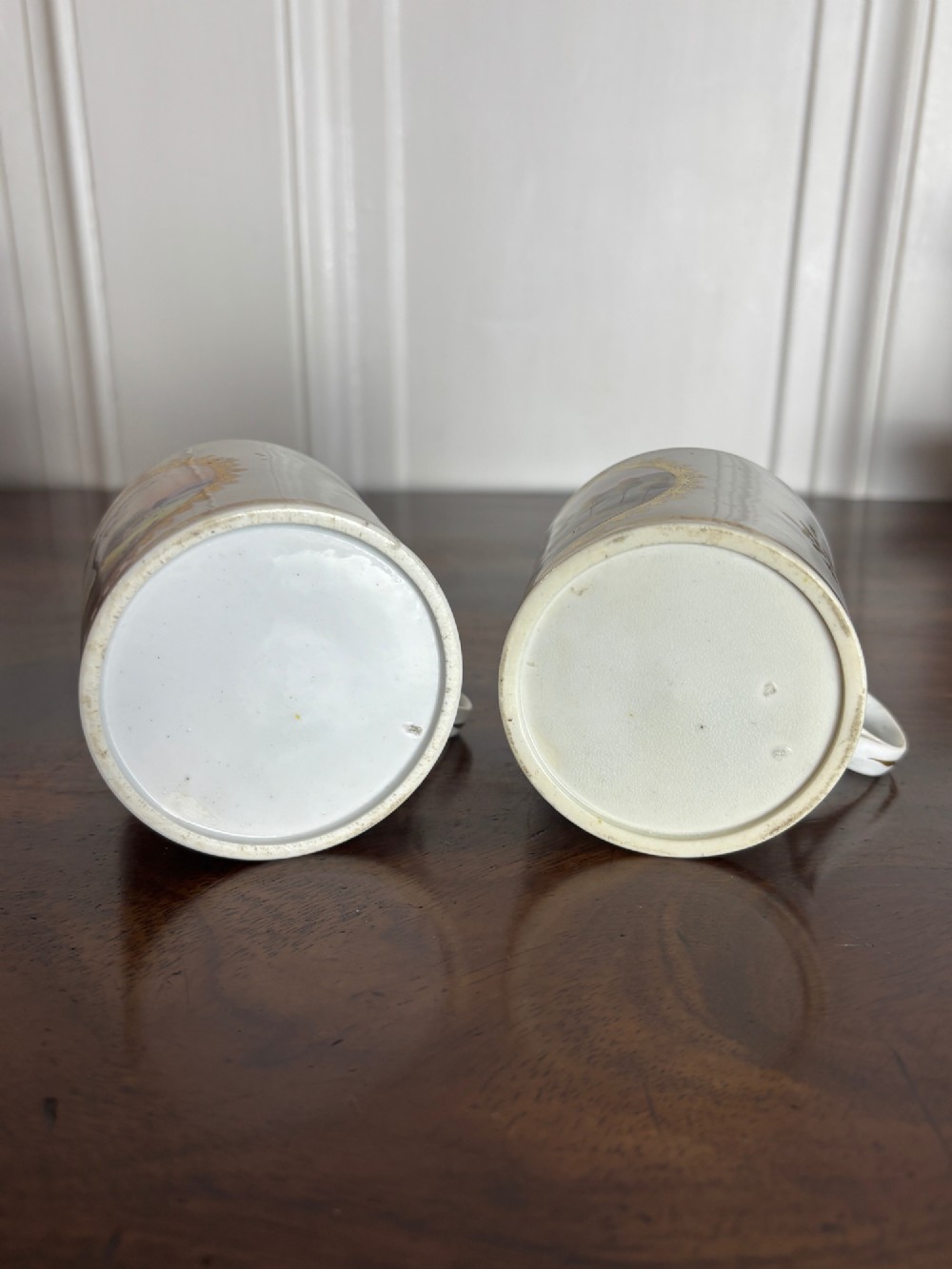 A pair of early nineteenth-century white porcelain coffee cans featuring hand-painted oval landscape vignettes framed with gilded borders. View VII