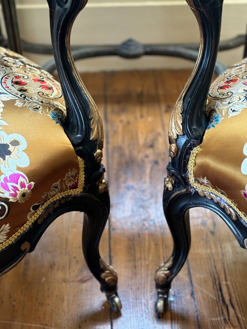 A pair of 19th-century French open armchairs with dark carved walnut frames, cabriole legs, and ornate gold silk brocade upholstery featuring floral motifs. View IV
