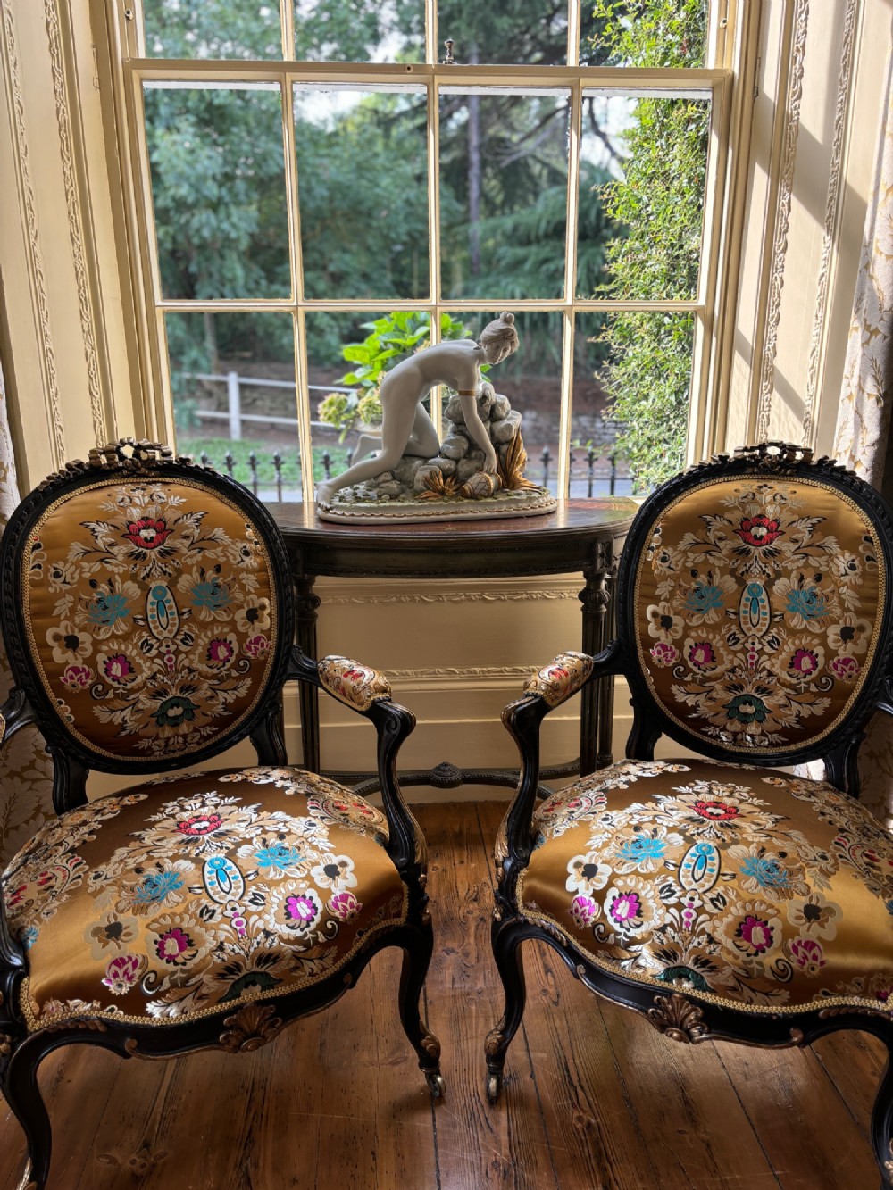 A pair of 19th-century French open armchairs with dark carved walnut frames, cabriole legs, and ornate gold silk brocade upholstery featuring floral motifs. View V