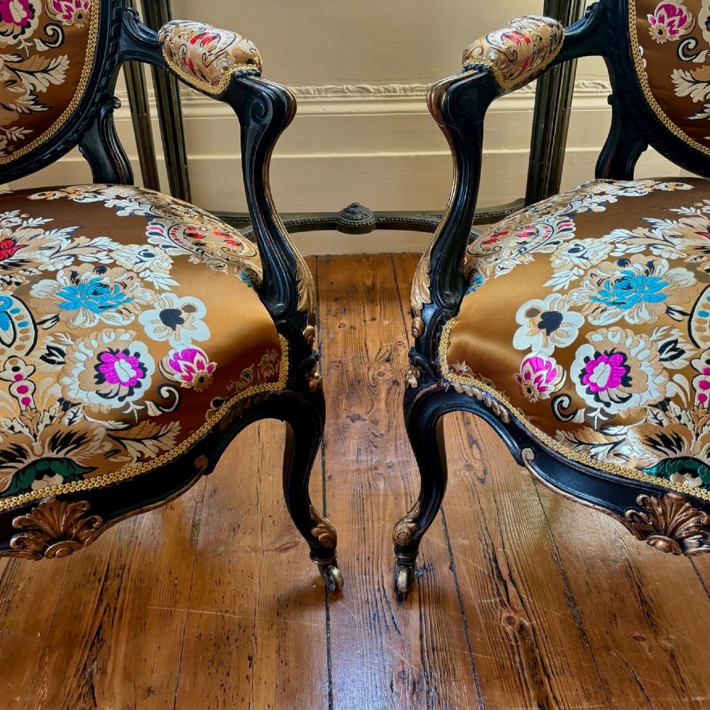 A pair of 19th-century French open armchairs with dark carved walnut frames, cabriole legs, and ornate gold silk brocade upholstery featuring floral motifs. View XII