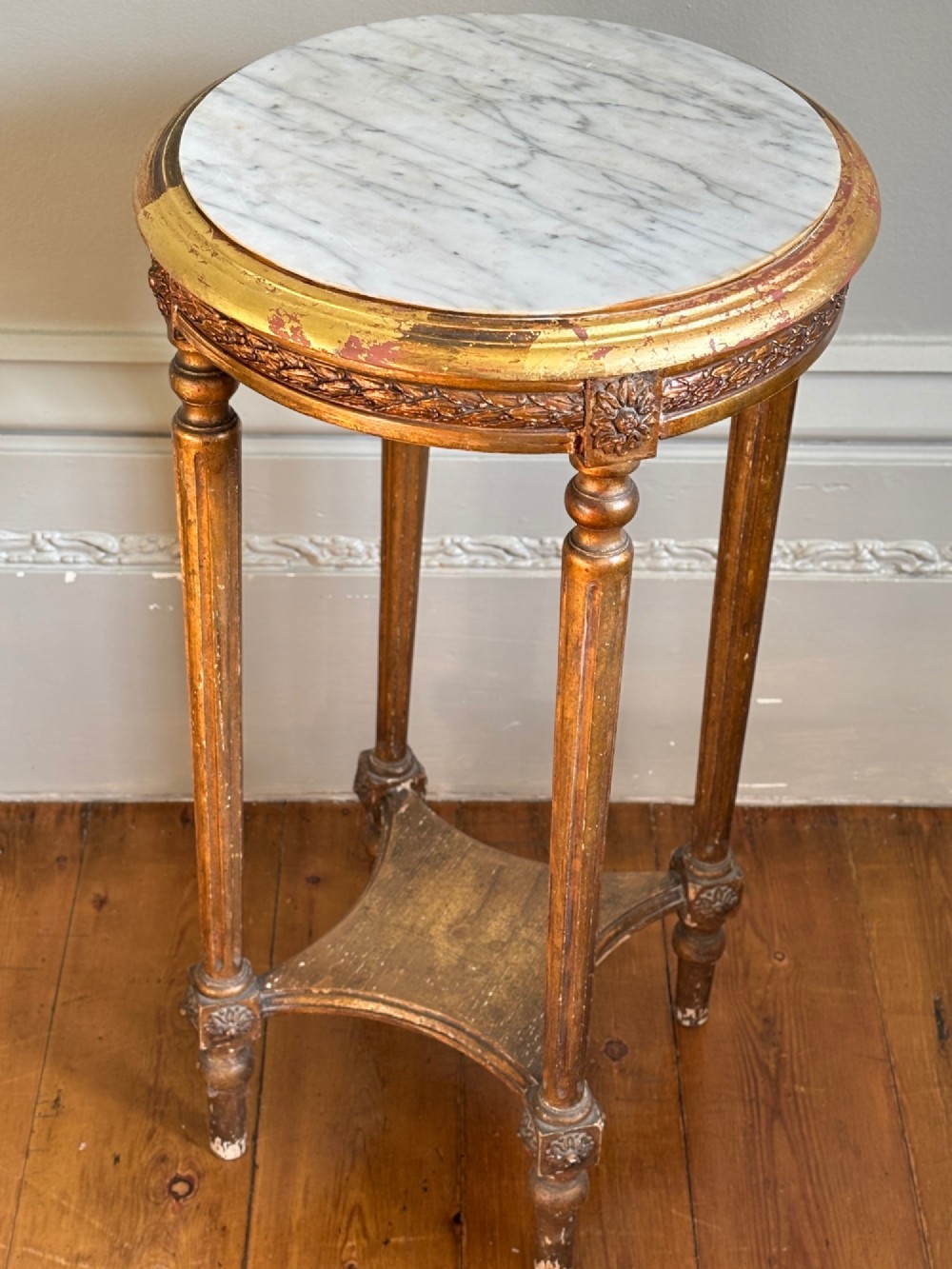 A French circa 1820 circular giltwood side table featuring a white marble top, fluted tapered legs, rosette carvings, and a low curved stretcher. View III