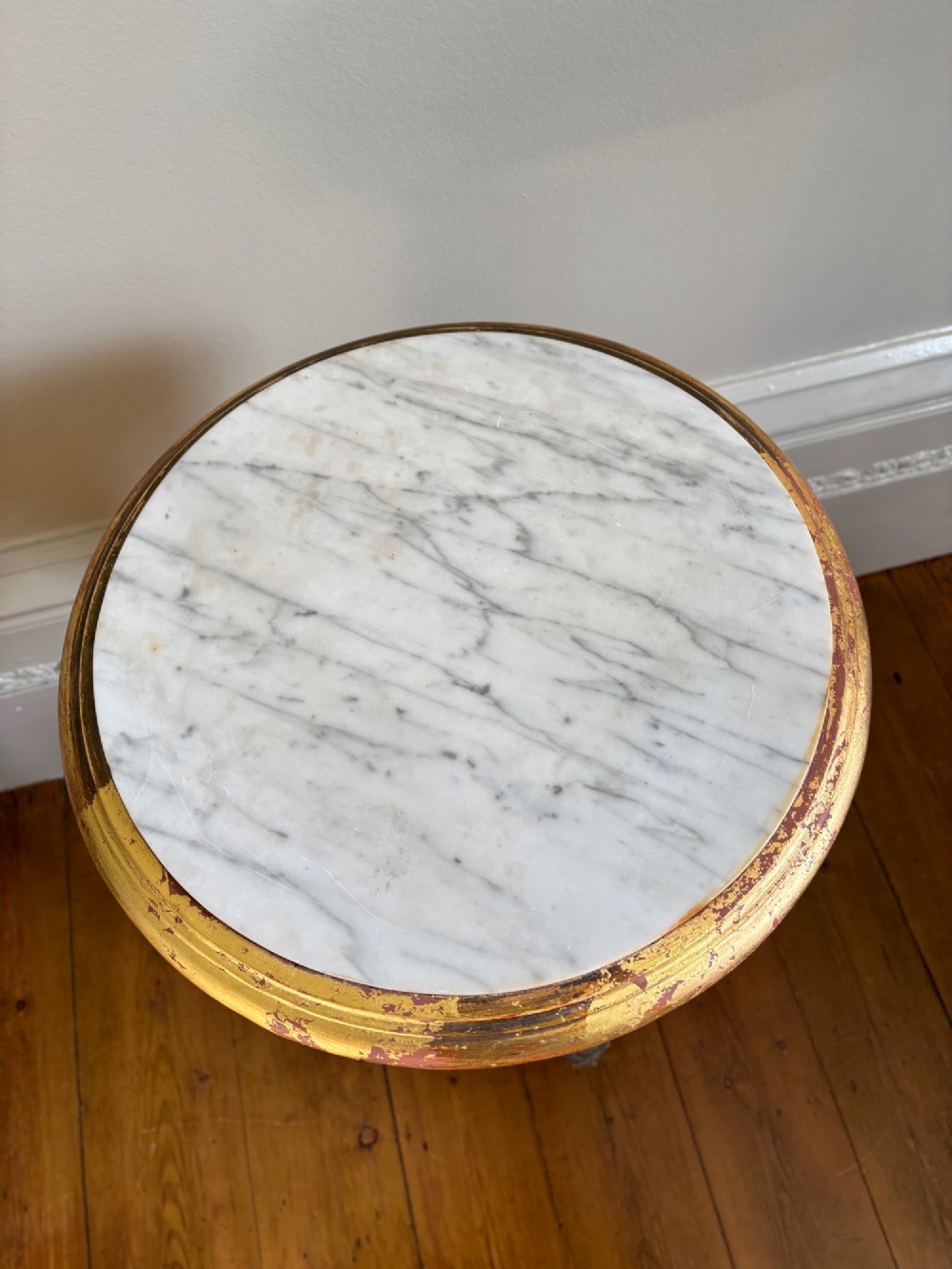 A French circa 1820 circular giltwood side table featuring a white marble top, fluted tapered legs, rosette carvings, and a low curved stretcher. View IV