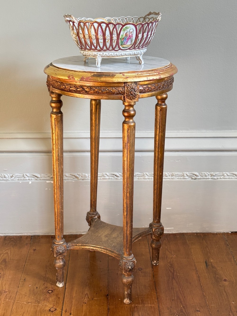 A French circa 1820 circular giltwood side table featuring a white marble top, fluted tapered legs, rosette carvings, and a low curved stretcher. View VII