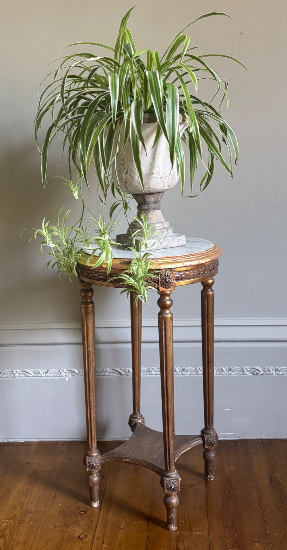 A French circa 1820 circular giltwood side table featuring a white marble top, fluted tapered legs, rosette carvings, and a low curved stretcher. View IX
