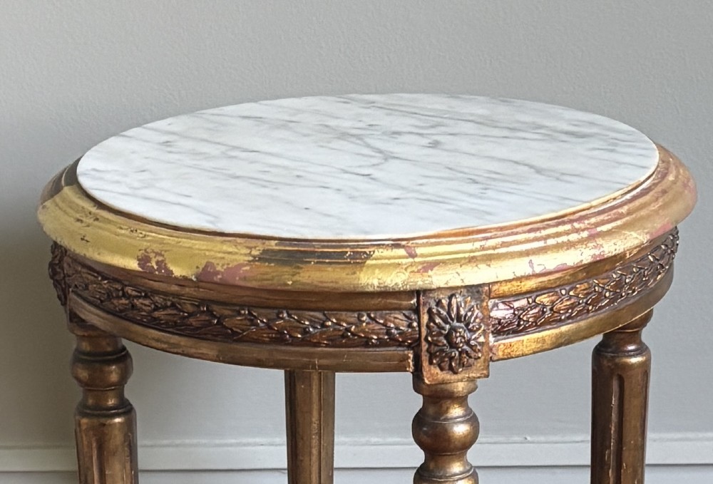 A French circa 1820 circular giltwood side table featuring a white marble top, fluted tapered legs, rosette carvings, and a low curved stretcher. View XI