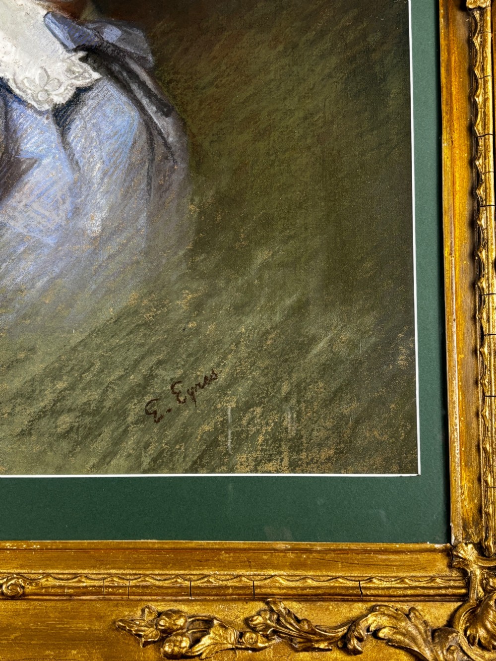 An antique pastel portrait of a blonde young boy wearing a blue garment and lace collar, presented in a dark green mount and an ornate gold gilt frame. View II