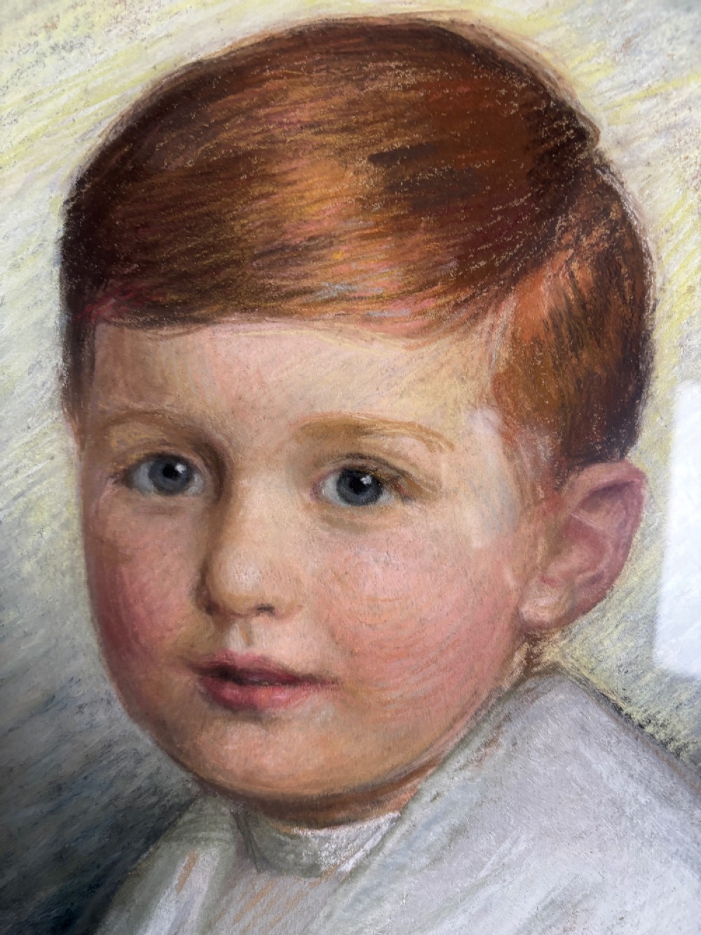 An oval Edwardian portrait of a young boy in a white sailor collar with a navy blue bow, set within a carved giltwood scroll frame. View III