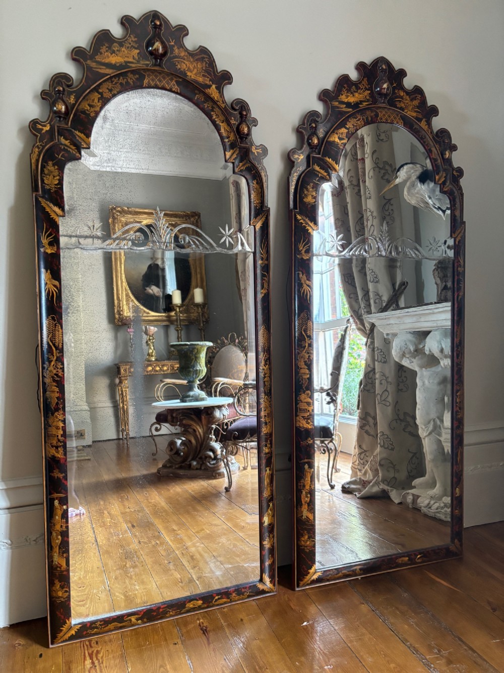 A pair of tall arched Queen Anne style pier mirrors featuring black lacquered frames decorated with gilded chinoiserie motifs and star-etched glass upper panels.
