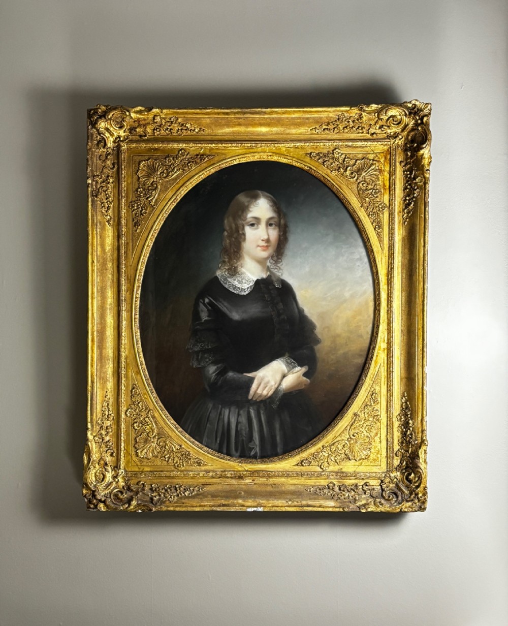 An oil portrait of a dark-haired woman in a black dress housed within an oval spandrel and a heavily carved gilt frame. View III