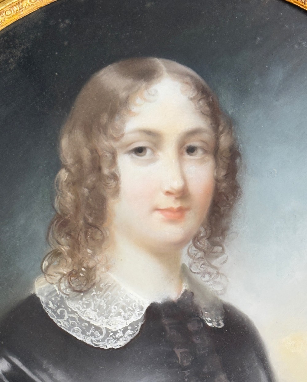 An oil portrait of a dark-haired woman in a black dress housed within an oval spandrel and a heavily carved gilt frame. View IV