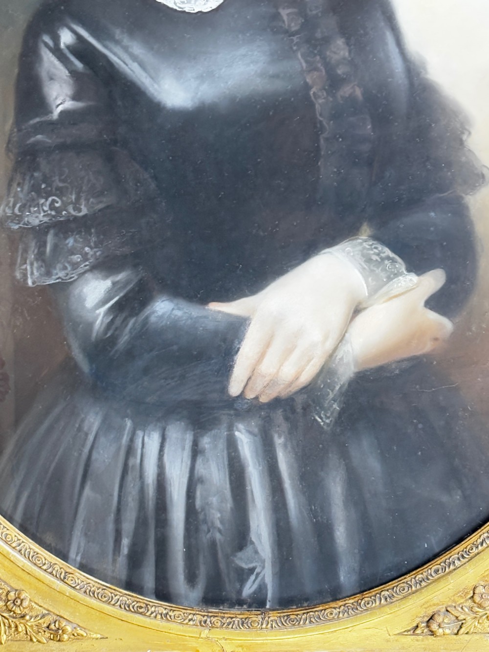 An oil portrait of a dark-haired woman in a black dress housed within an oval spandrel and a heavily carved gilt frame. View V