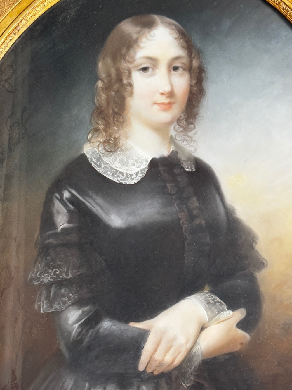 An oil portrait of a dark-haired woman in a black dress housed within an oval spandrel and a heavily carved gilt frame. View VI