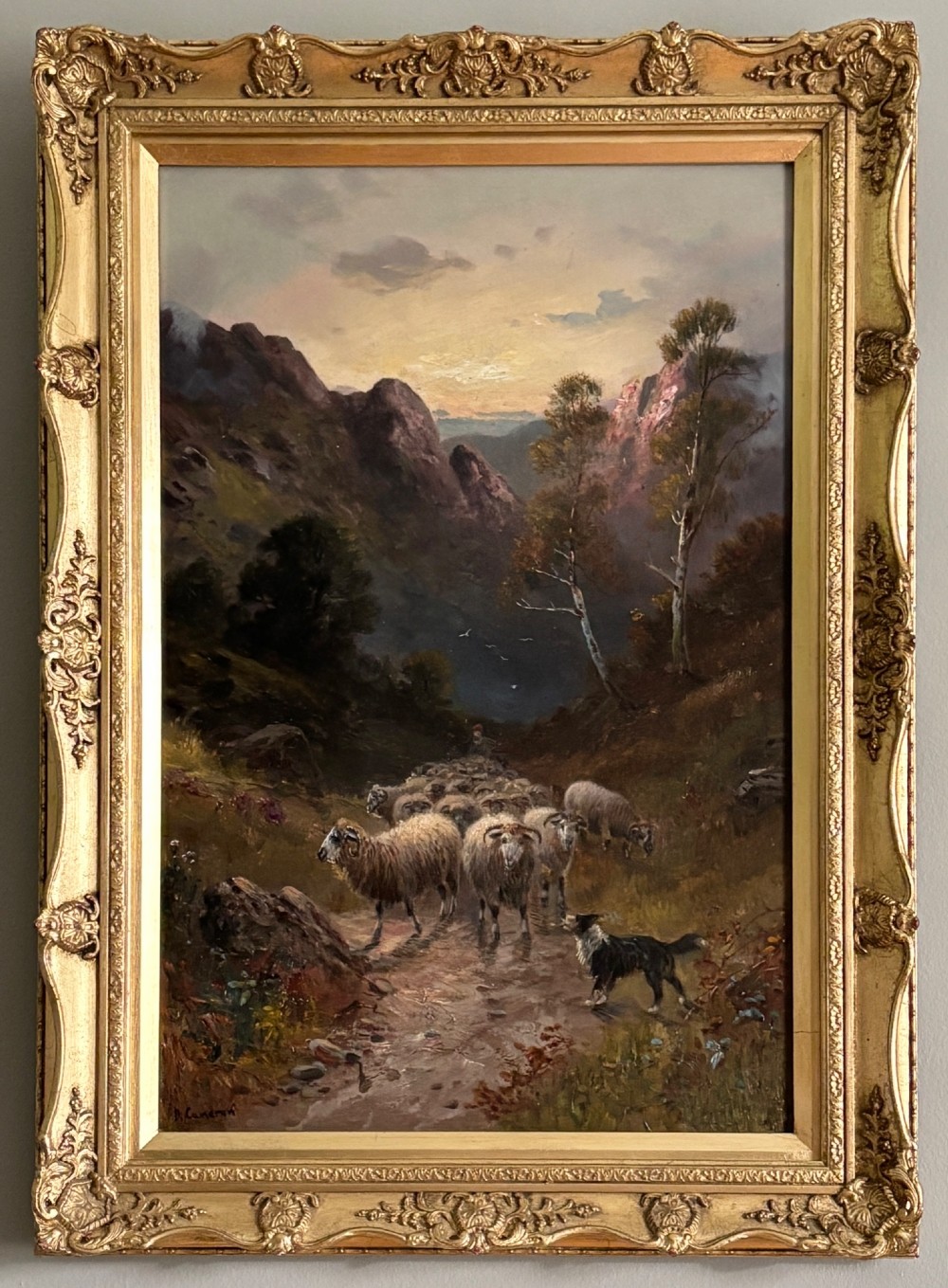 An oil painting on canvas depicting a flock of sheep and a sheepdog on a Scottish mountain path at sunset, presented in an ornate giltwood frame. View II