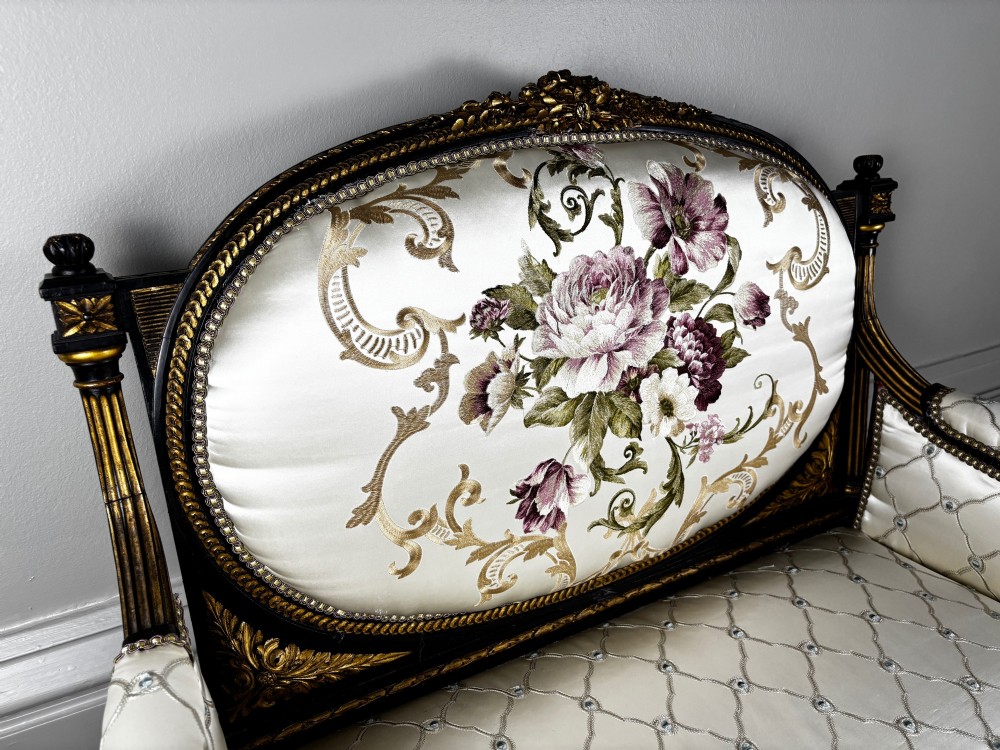 A French Louis XVI style settee featuring an ebonised frame with gilt details and cream silk upholstery. View IV