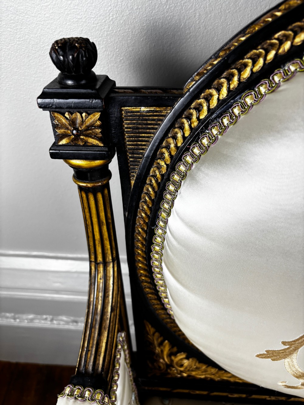 A French Louis XVI style settee featuring an ebonised frame with gilt details and cream silk upholstery. View V