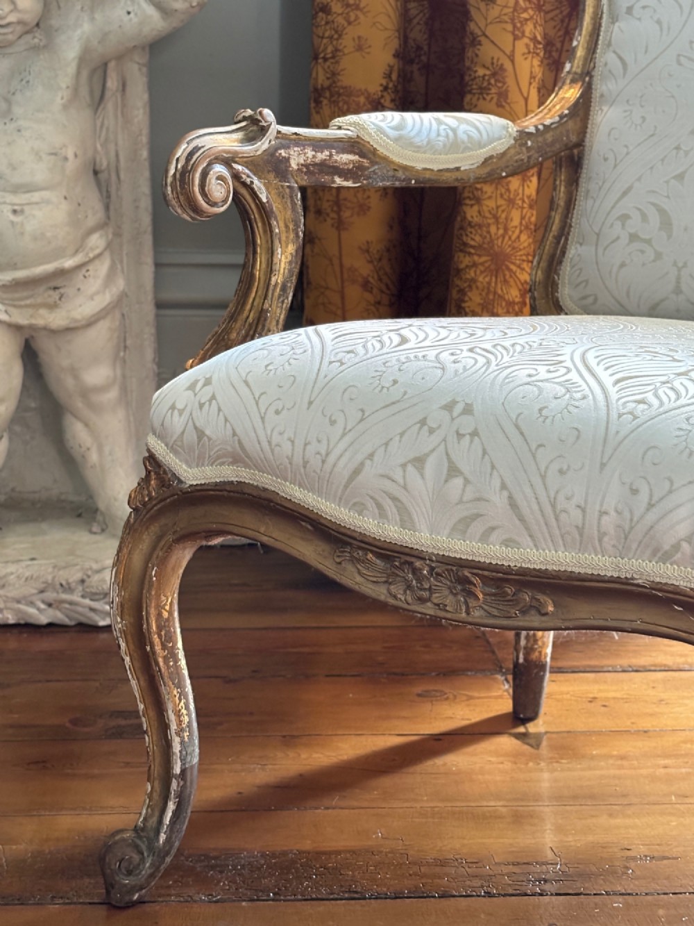 A Louis XV style open armchair featuring a distressed giltwood frame with cabriole legs, padded manchettes, and cream patterned silk damask upholstery. View IV