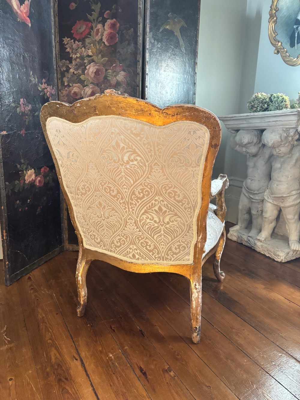 A Louis XV style open armchair featuring a distressed giltwood frame with cabriole legs, padded manchettes, and cream patterned silk damask upholstery. View IX