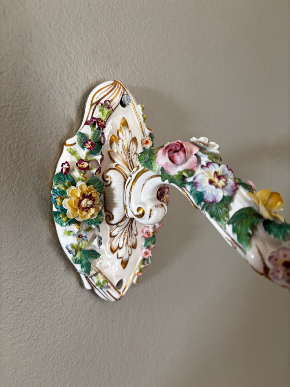 An antique Meissen hard-paste porcelain single candle wall sconce decorated with applied colourful flowers, gilt rococo scrollwork backplate, and a petal-shaped candle socket. View III