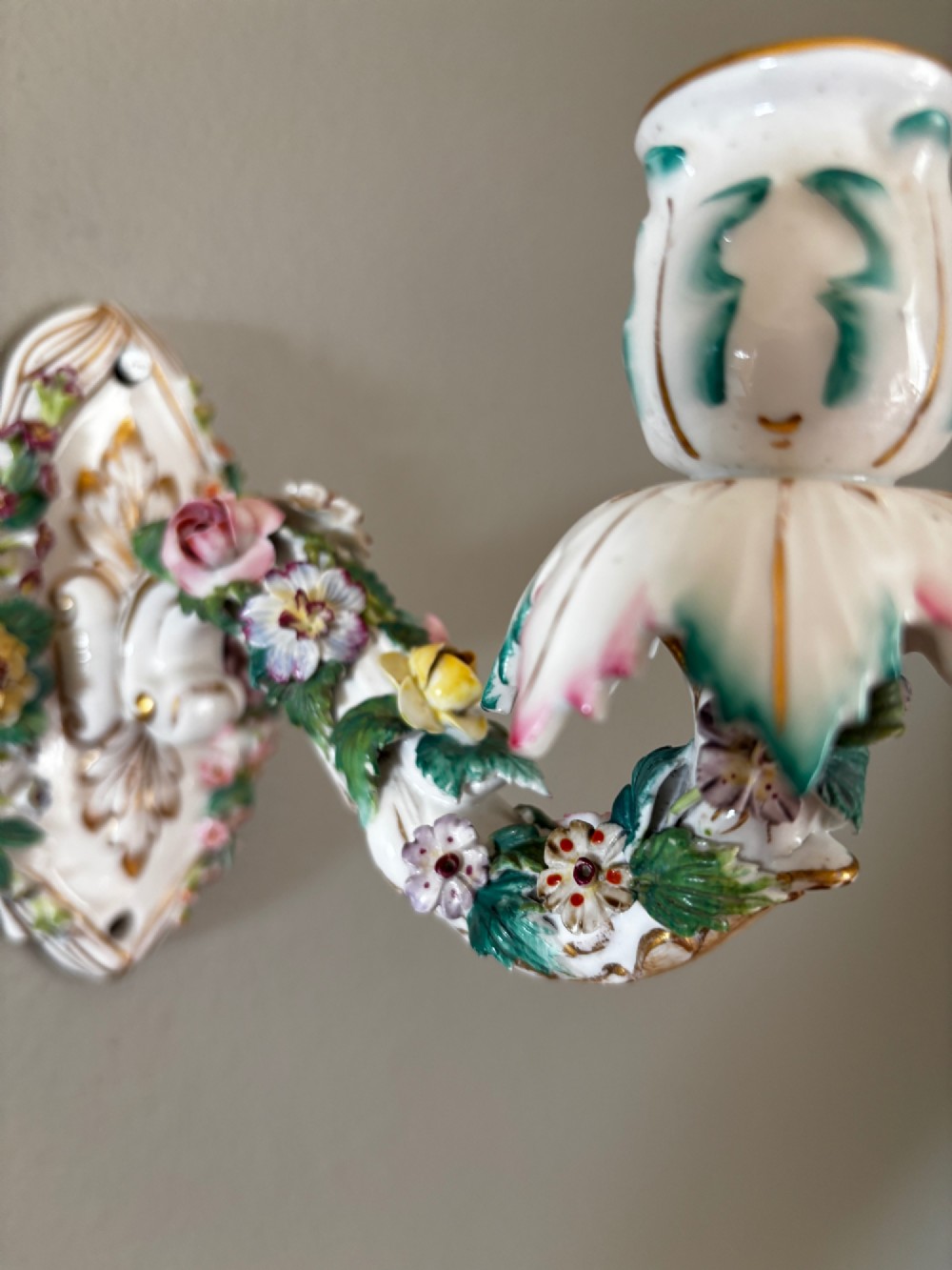An antique Meissen hard-paste porcelain single candle wall sconce decorated with applied colourful flowers, gilt rococo scrollwork backplate, and a petal-shaped candle socket. View IV