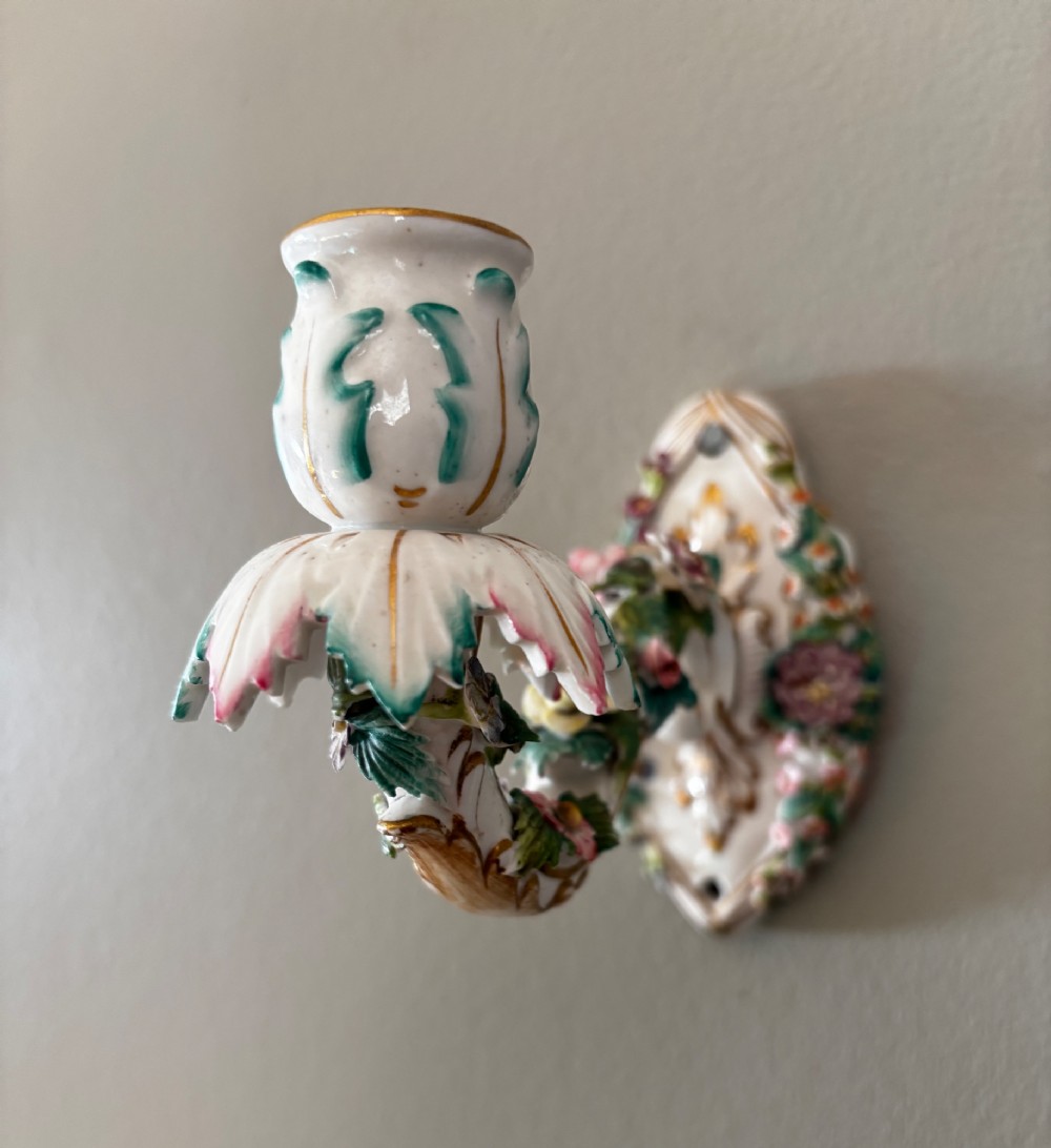 An antique Meissen hard-paste porcelain single candle wall sconce decorated with applied colourful flowers, gilt rococo scrollwork backplate, and a petal-shaped candle socket. View V