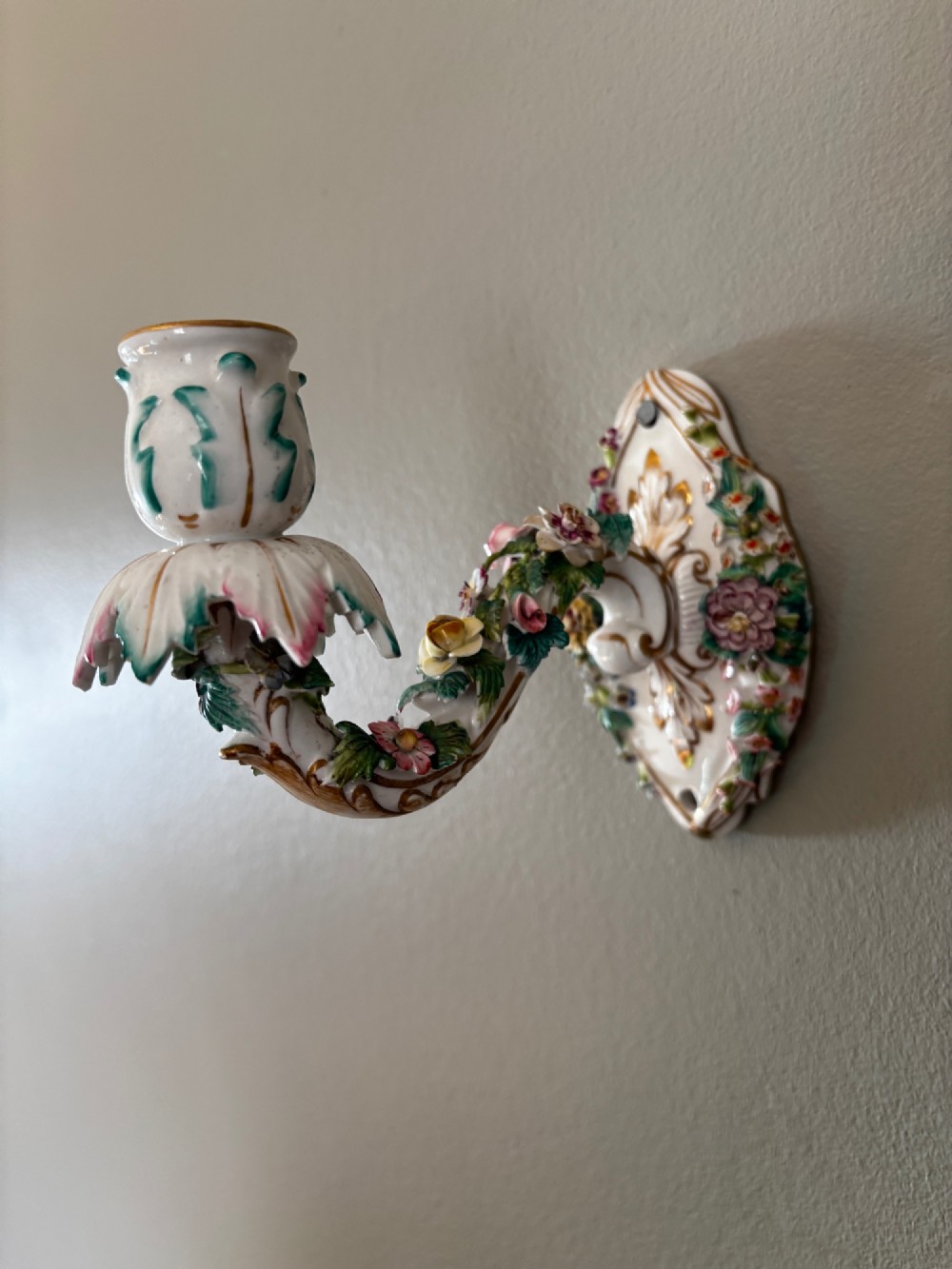 An antique Meissen hard-paste porcelain single candle wall sconce decorated with applied colourful flowers, gilt rococo scrollwork backplate, and a petal-shaped candle socket. View VI