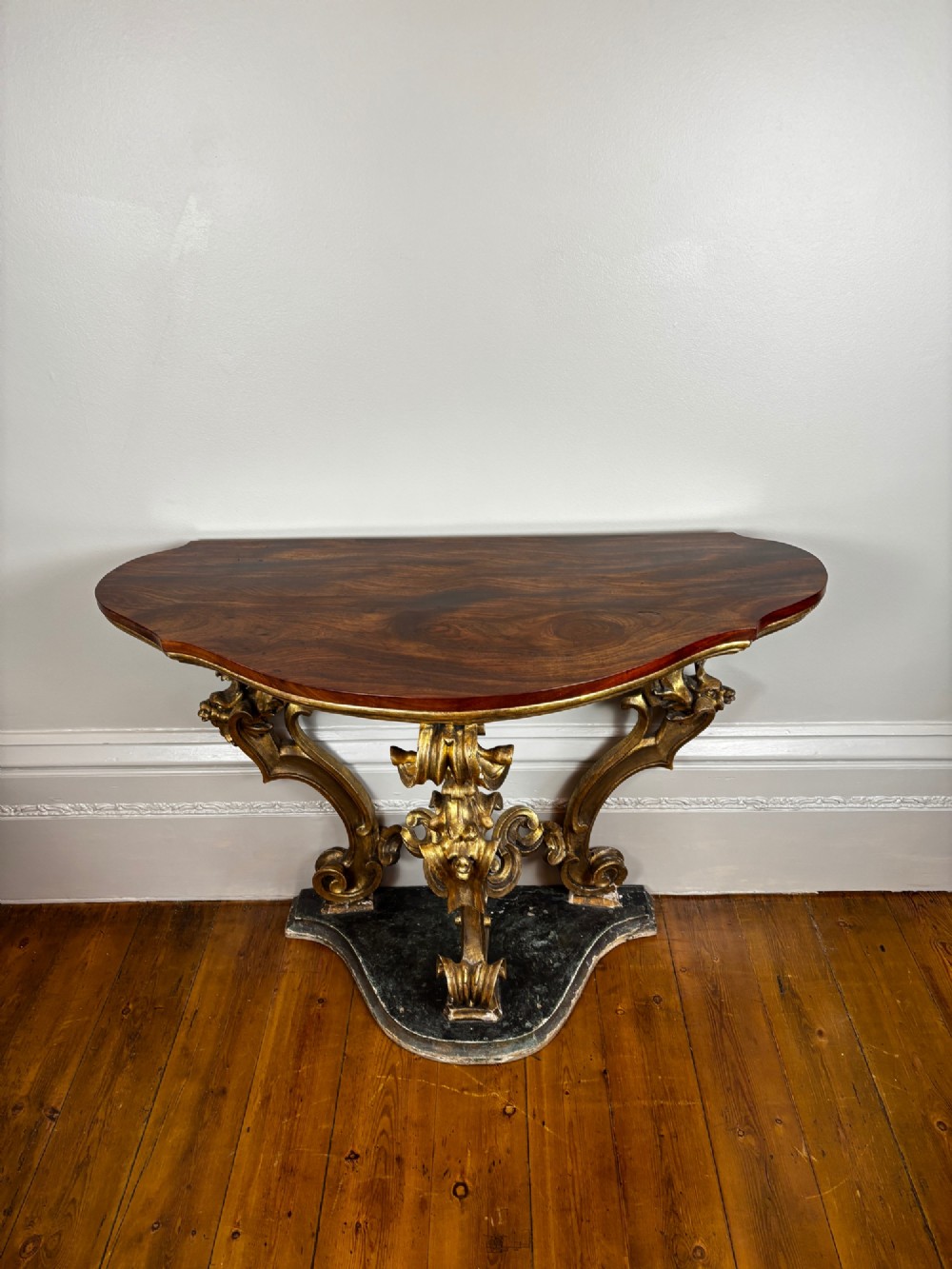 Late eighteenth-century Venetian giltwood console table featuring carved scroll supports, a shaped plinth base, and a polished dark timber top. View II