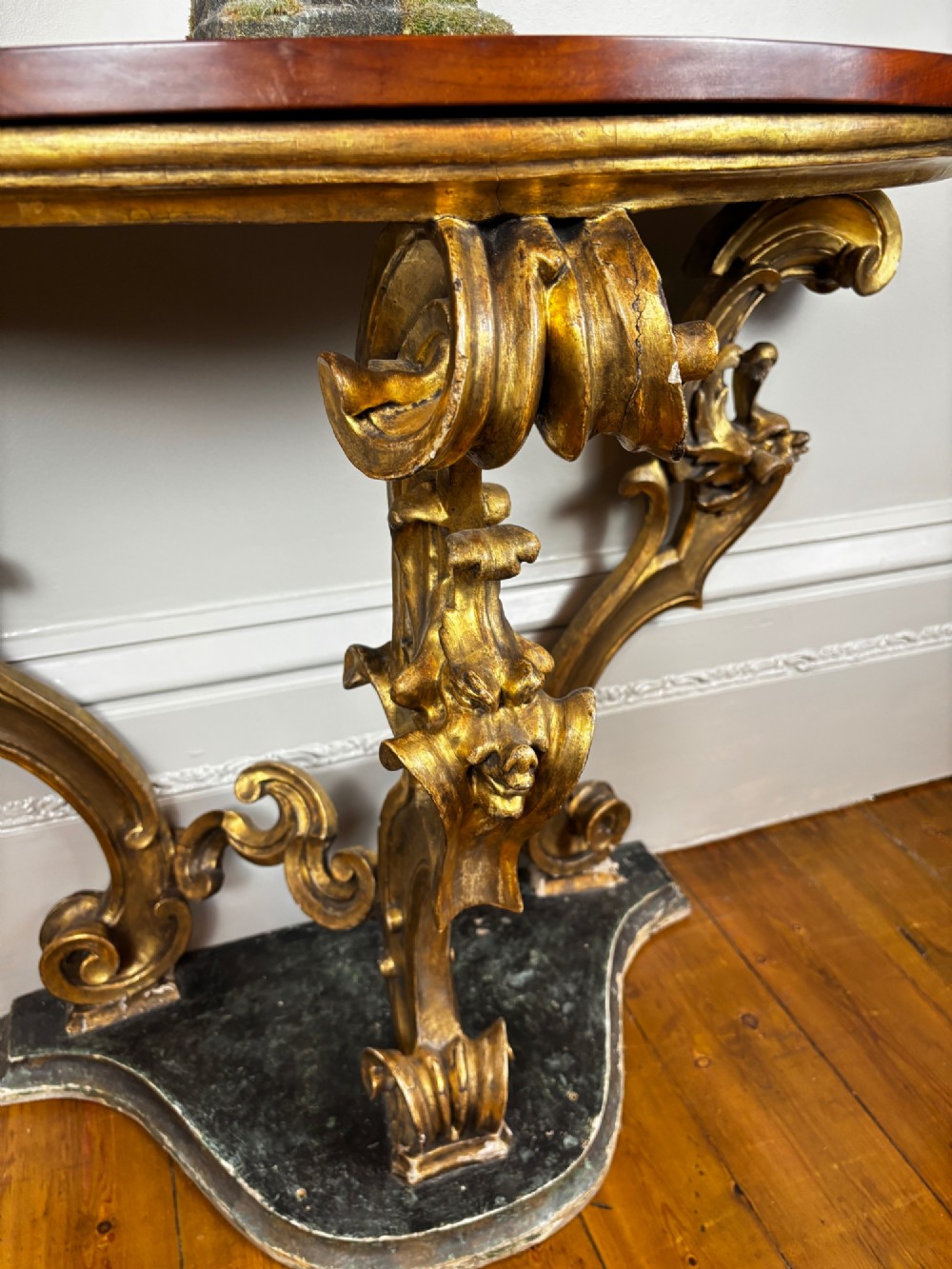 Late eighteenth-century Venetian giltwood console table featuring carved scroll supports, a shaped plinth base, and a polished dark timber top. View III