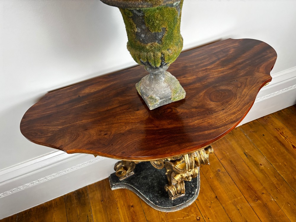 Late eighteenth-century Venetian giltwood console table featuring carved scroll supports, a shaped plinth base, and a polished dark timber top. View VII