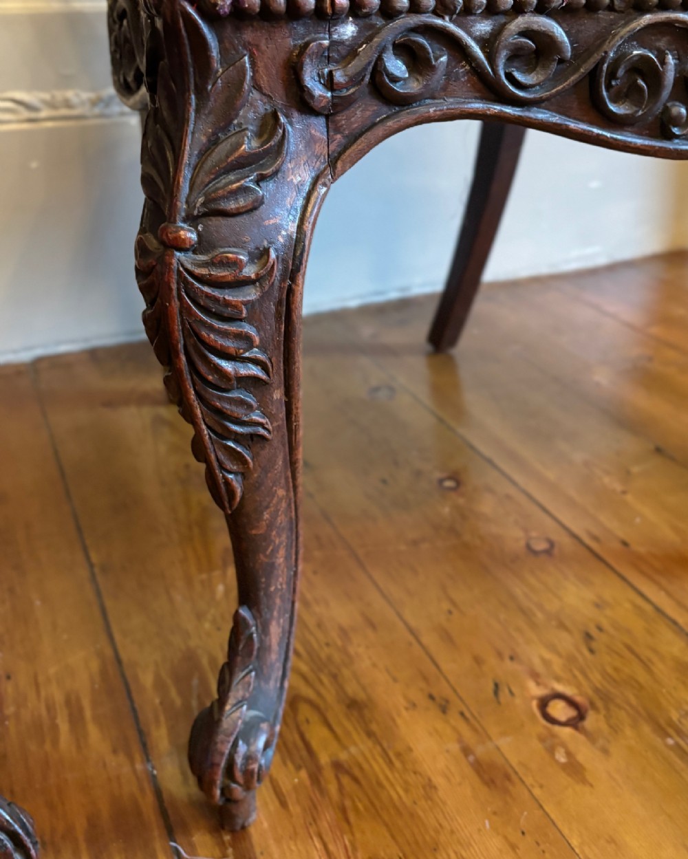 A pair of 19th-century Anglo-Indian padauk wood side chairs featuring intricately carved openwork backs, cabriole legs, and bright pink silk seat cushions. View IV