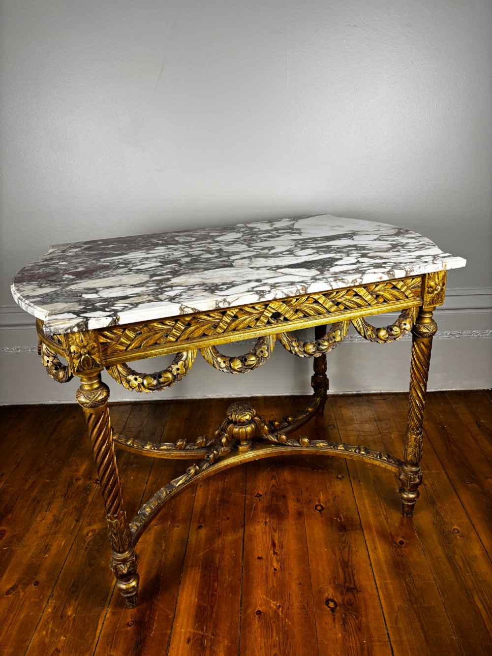 An early 20th-century French Louis XV Revival giltwood console table with a carved openwork apron, spiralled legs, curved stretcher, and fitted white marble top. View II