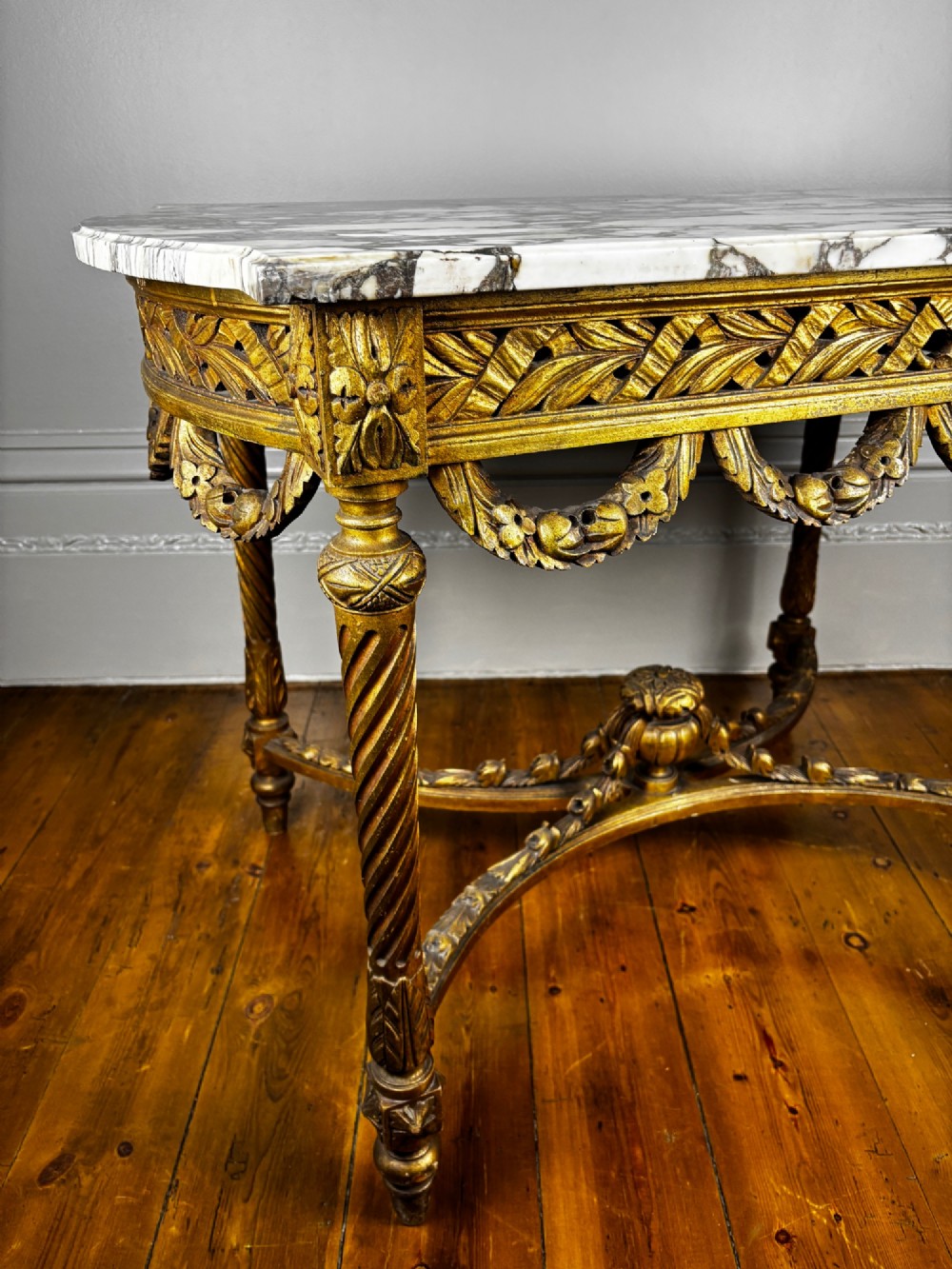 An early 20th-century French Louis XV Revival giltwood console table with a carved openwork apron, spiralled legs, curved stretcher, and fitted white marble top. View IV