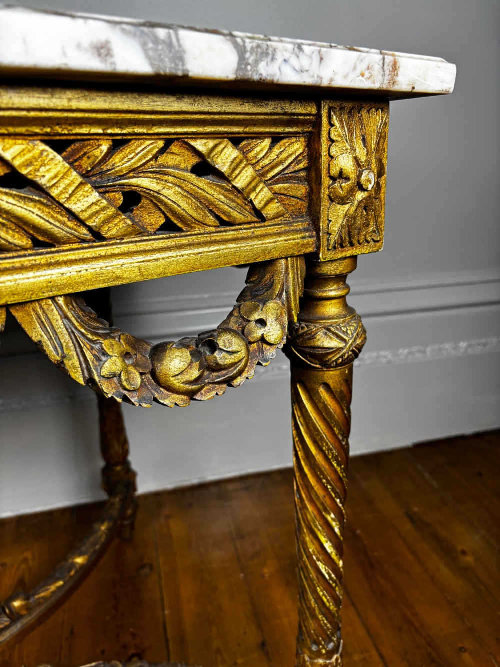 An early 20th-century French Louis XV Revival giltwood console table with a carved openwork apron, spiralled legs, curved stretcher, and fitted white marble top. View VI