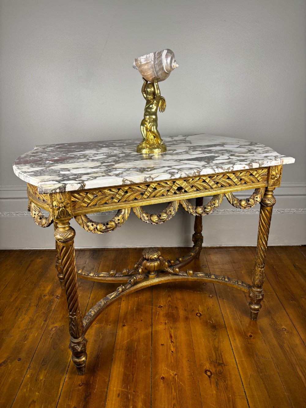 An early 20th-century French Louis XV Revival giltwood console table with a carved openwork apron, spiralled legs, curved stretcher, and fitted white marble top. View VII