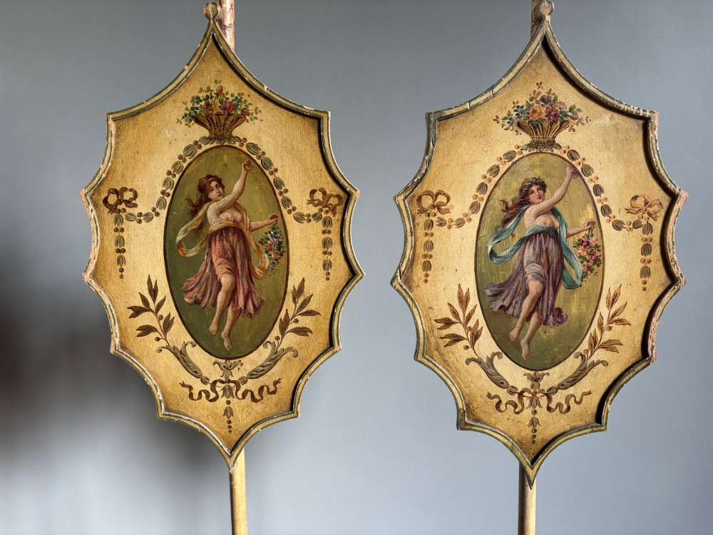 A pair of antique Georgian cream painted Hepplewhite pole screens featuring central oval vignettes depicting classical female figures with floral surround details on tripod spade-foot bases. View VIII