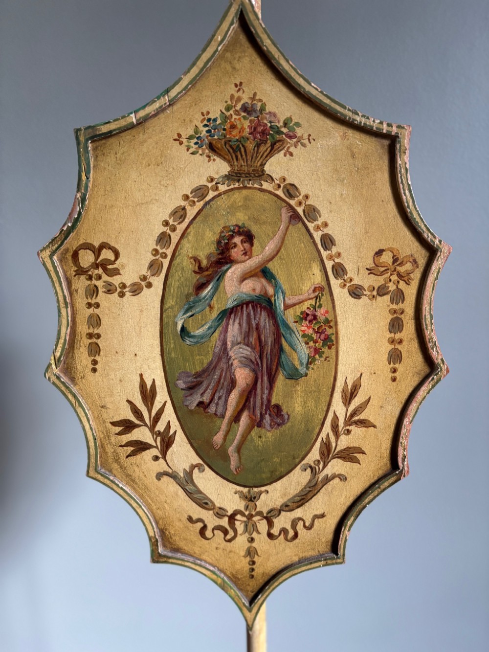 A pair of antique Georgian cream painted Hepplewhite pole screens featuring central oval vignettes depicting classical female figures with floral surround details on tripod spade-foot bases. View XI