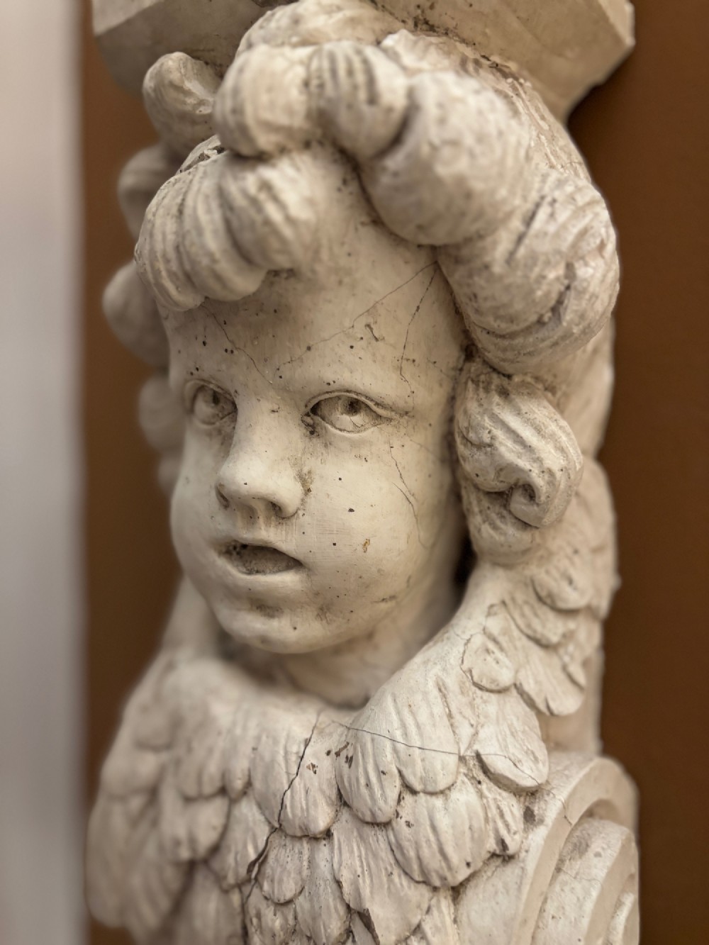 A carved off-white 19th-century wall corbel featuring a detailed winged putto head above layered acanthus leaves. View III