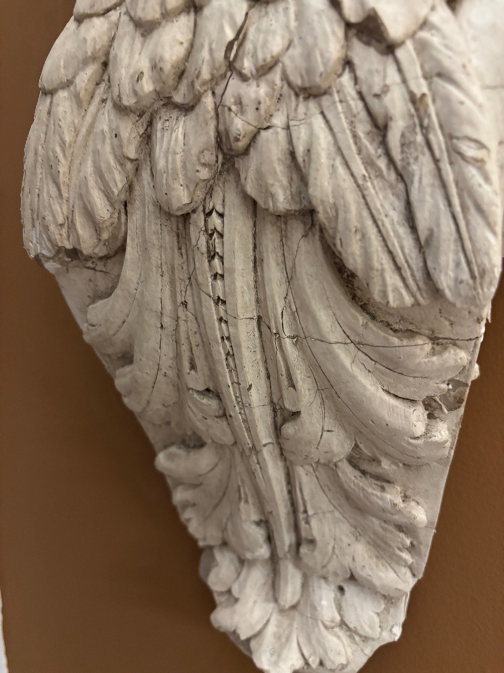 A carved off-white 19th-century wall corbel featuring a detailed winged putto head above layered acanthus leaves. View IV