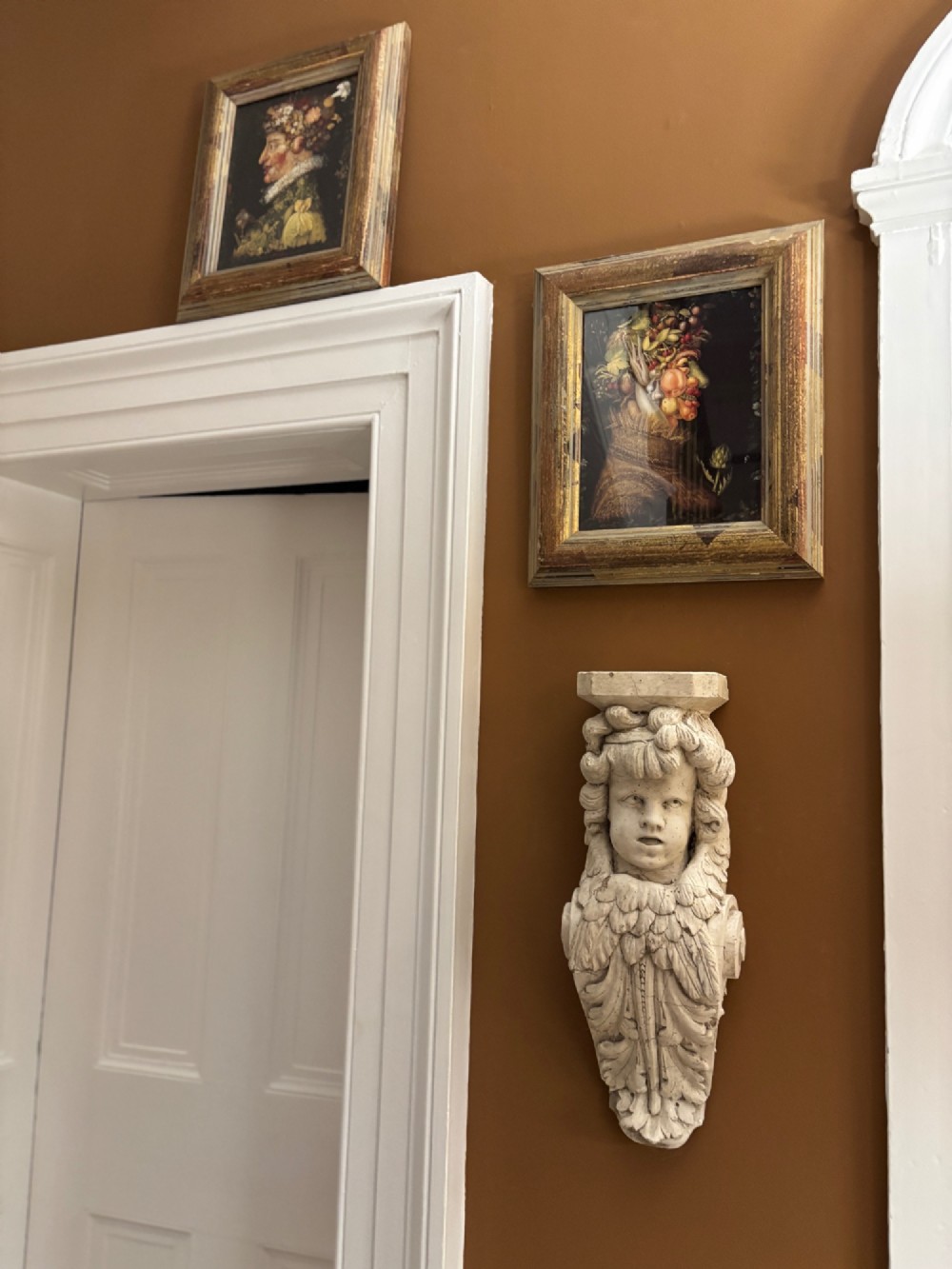A carved off-white 19th-century wall corbel featuring a detailed winged putto head above layered acanthus leaves. View VIII