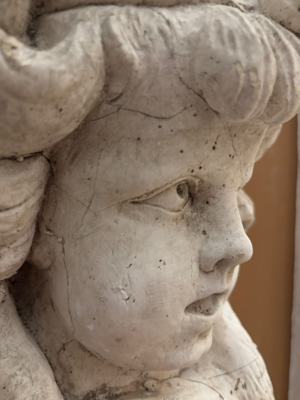 A carved off-white 19th-century wall corbel featuring a detailed winged putto head above layered acanthus leaves. View XII