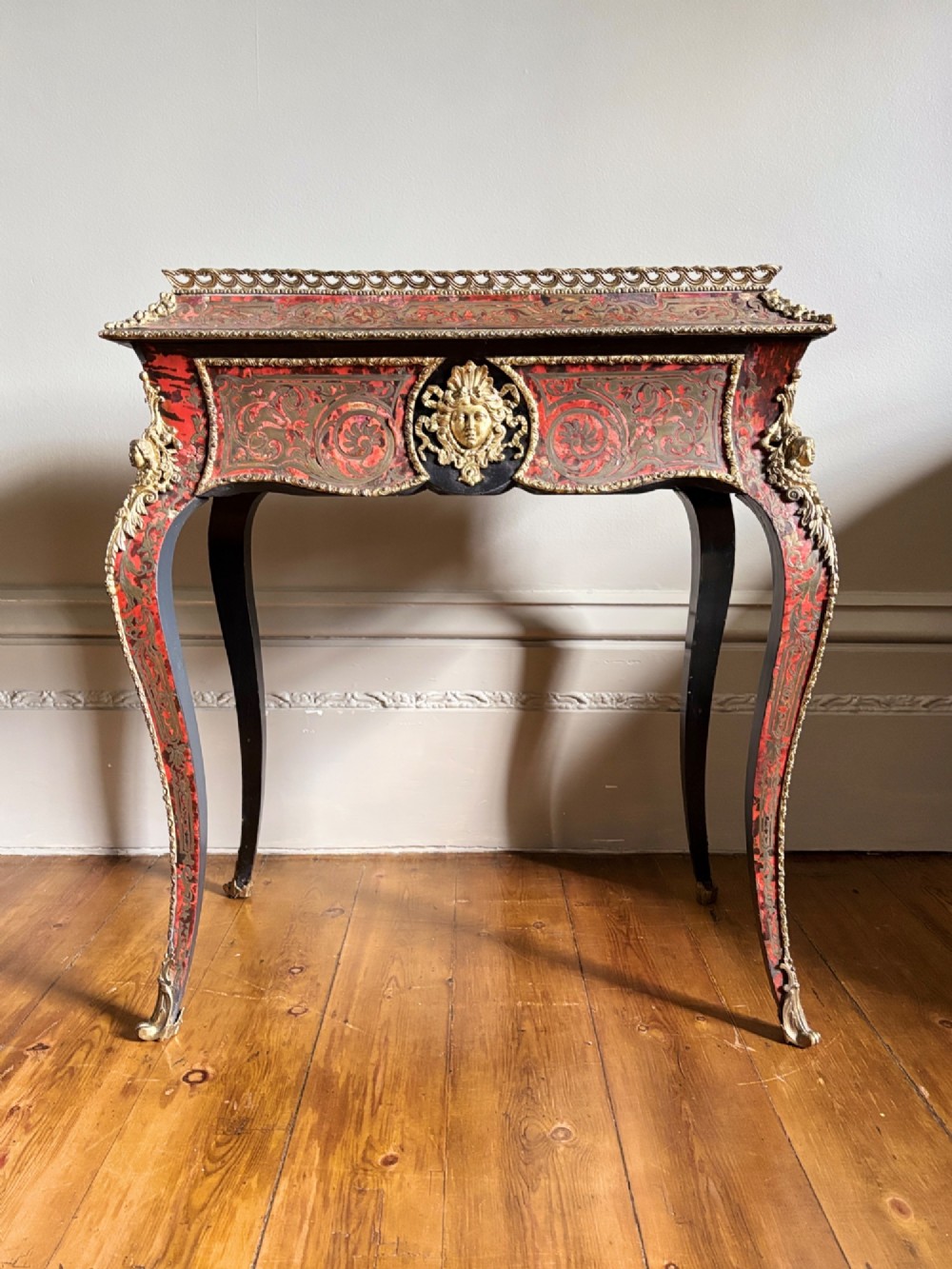 A 19th-century French Napoleon III jardiniere stand featuring red tortoiseshell and brass marquetry inlay, gilt bronze mounts, and curved cabriole legs.