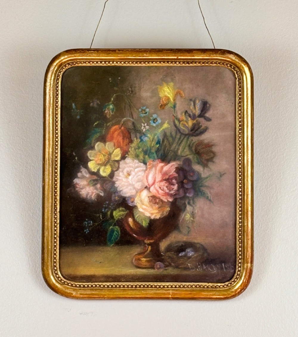 A framed 1815 Georgian pastel painting depicting a floral bouquet in an urn with a small birds nest on a ledge, enclosed in a gilded frame with rounded corners.