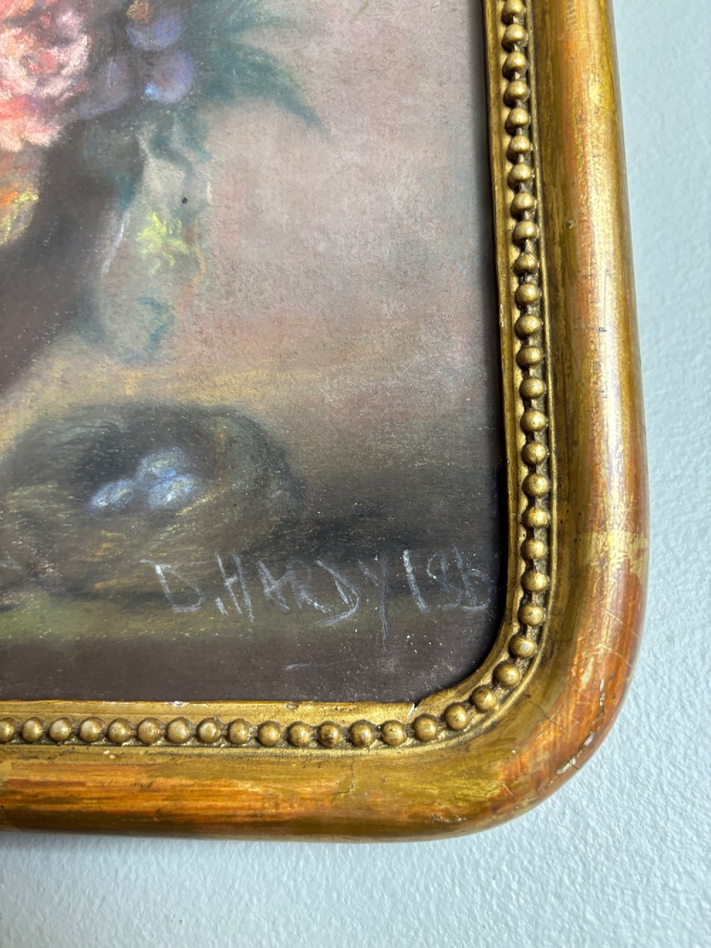 A framed 1815 Georgian pastel painting depicting a floral bouquet in an urn with a small birds nest on a ledge, enclosed in a gilded frame with rounded corners. View IV