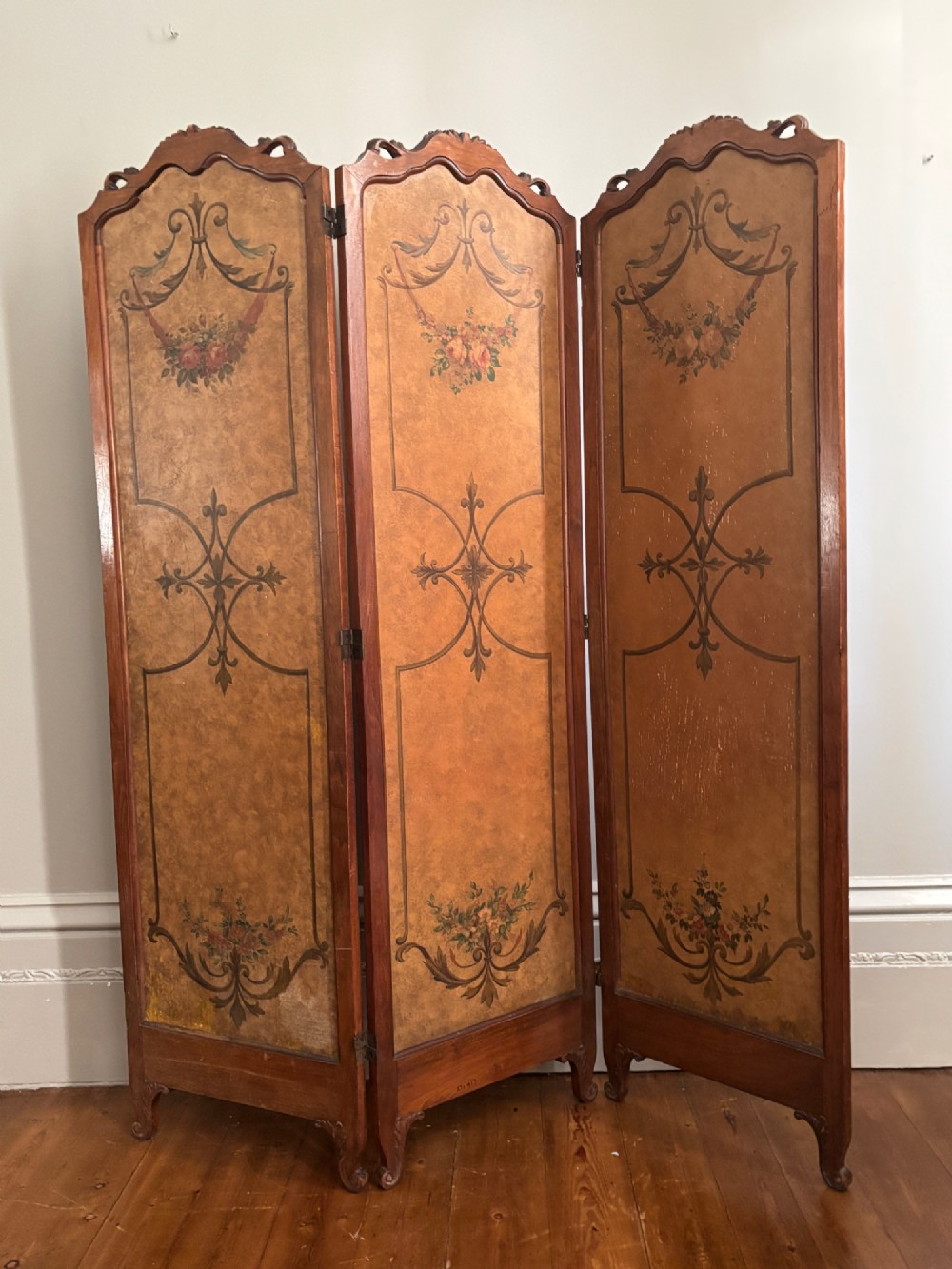 A French three-fold walnut screen featuring carved crestings and hand-painted panels depicting pastoral scenes, floral garlands, and musical trophies. View III