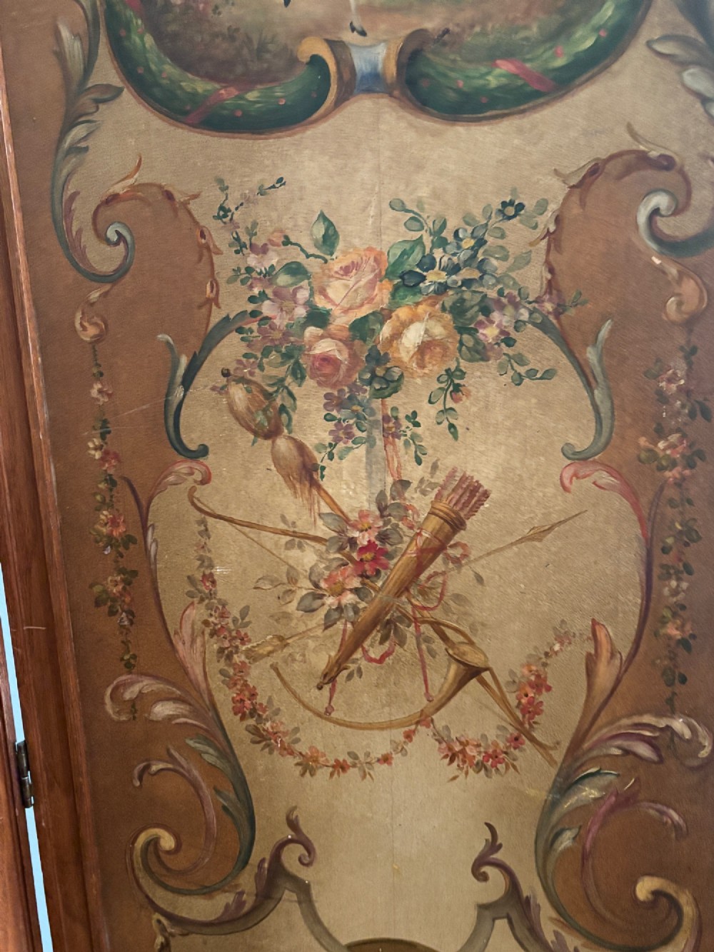 A French three-fold walnut screen featuring carved crestings and hand-painted panels depicting pastoral scenes, floral garlands, and musical trophies. View X