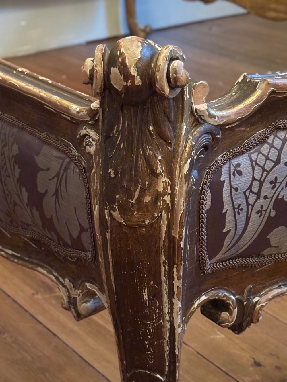 A 19th-century Italian Rococo giltwood bed frame with an ornate carved headboard and footboard upholstered in patterned damask fabric. View V
