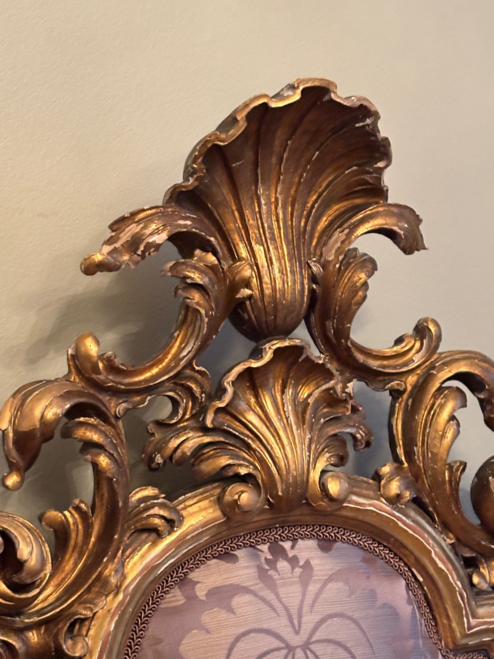 A 19th-century Italian Rococo giltwood bed frame with an ornate carved headboard and footboard upholstered in patterned damask fabric. View X