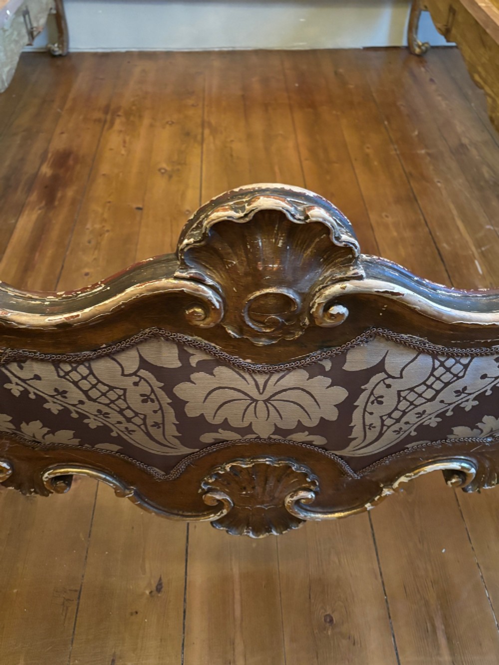 A 19th-century Italian Rococo giltwood bed frame with an ornate carved headboard and footboard upholstered in patterned damask fabric. View XI