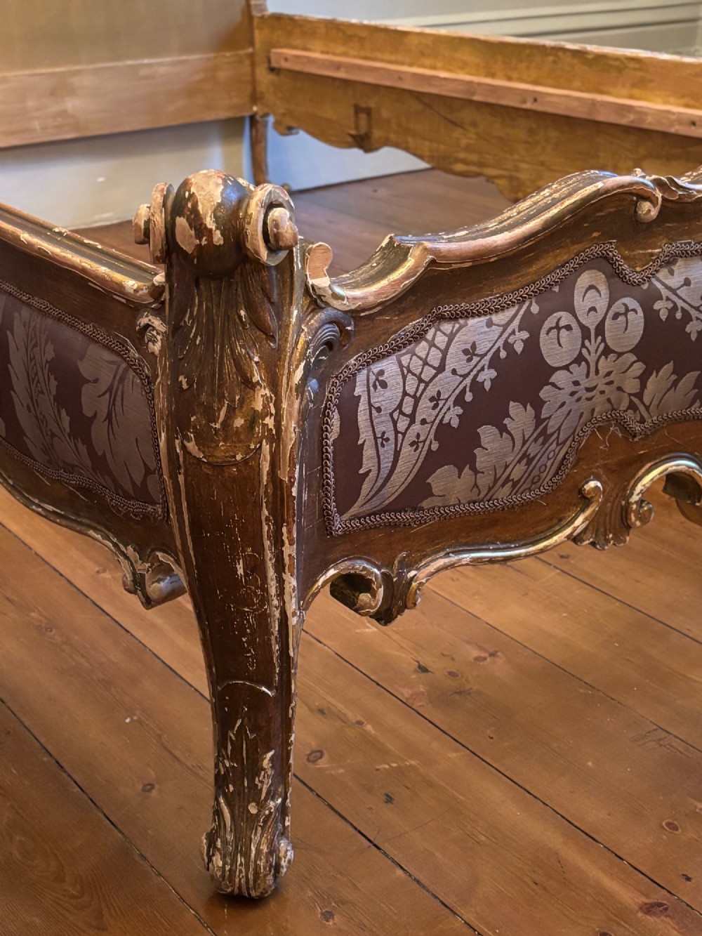 A 19th-century Italian Rococo giltwood bed frame with an ornate carved headboard and footboard upholstered in patterned damask fabric. View XIII