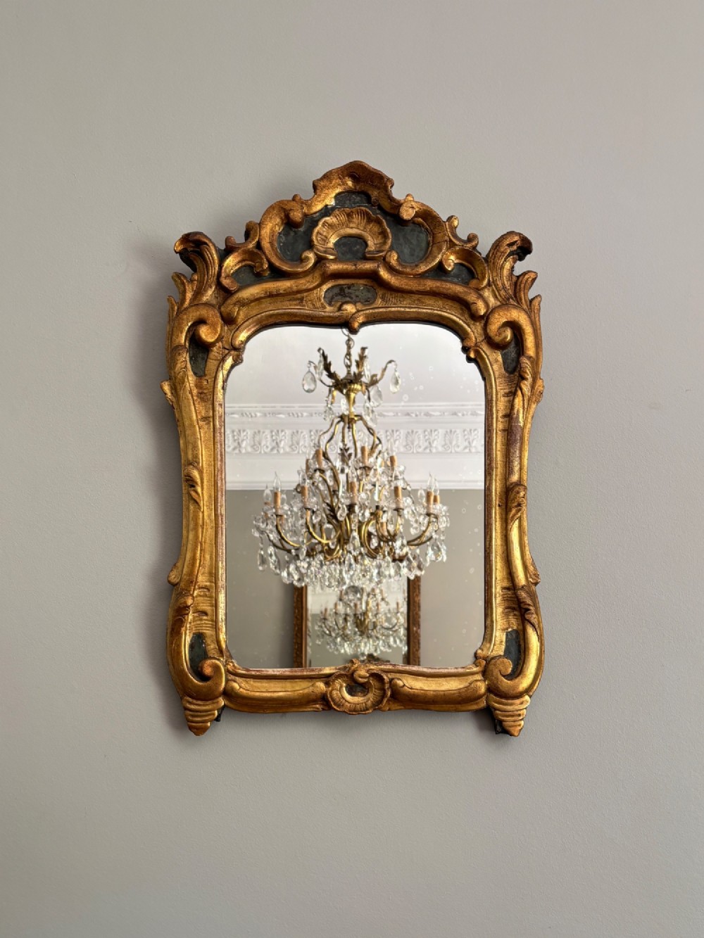An 18th-century French Louis XV giltwood wall mirror featuring a carved rocaille shell cresting, scrolling side contours, and an arched glass plate. View II