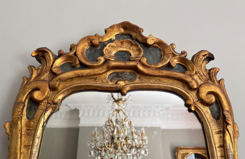 An 18th-century French Louis XV giltwood wall mirror featuring a carved rocaille shell cresting, scrolling side contours, and an arched glass plate. View III